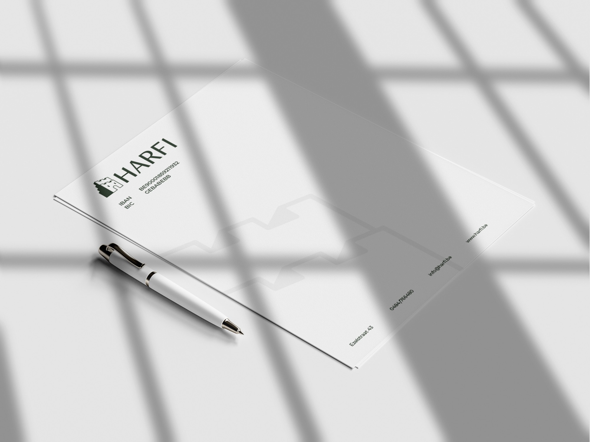 Mockup van het briefpapier van Harfi met een pen, in het zonlicht
