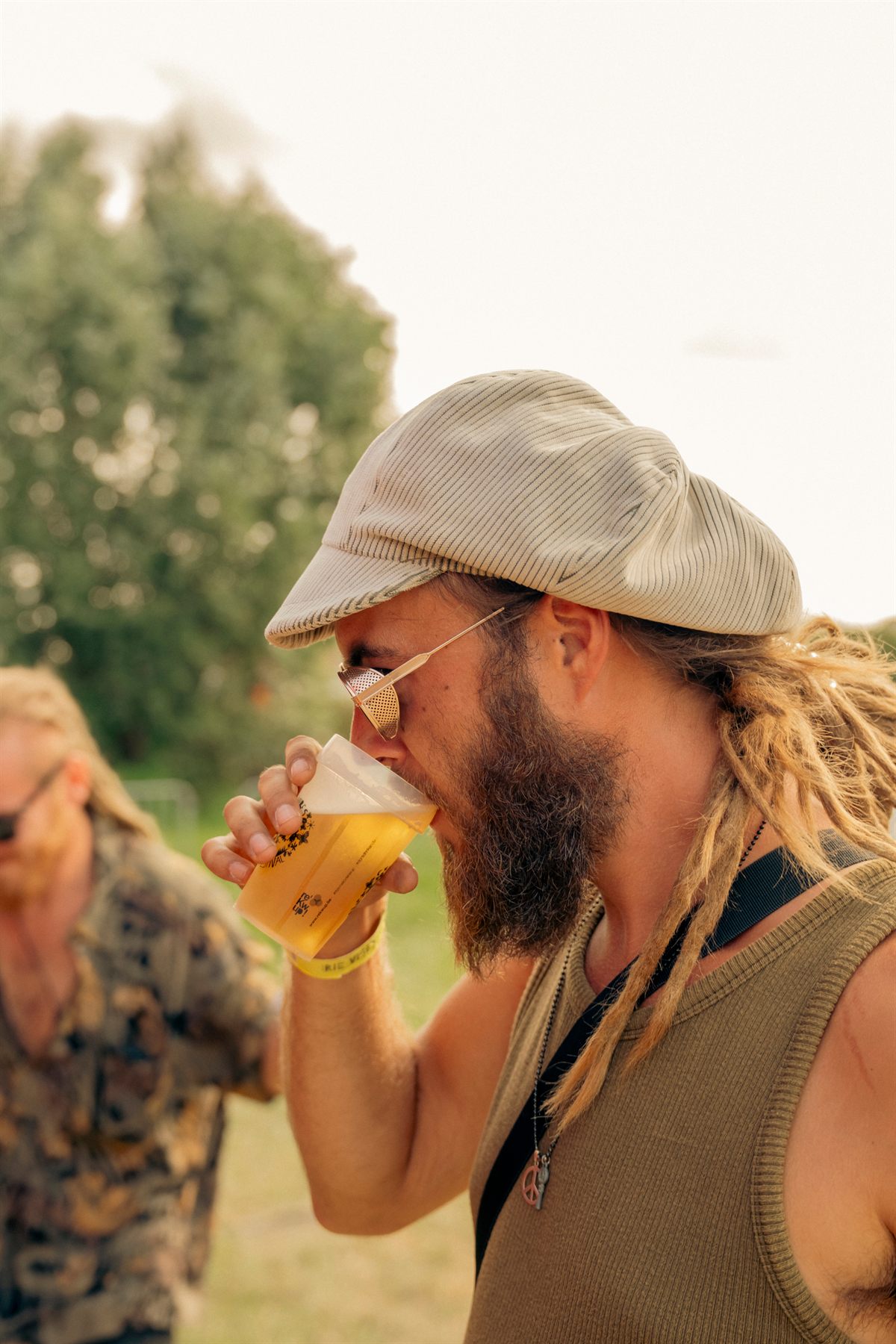 Man met pet die van zijn bier drinkt