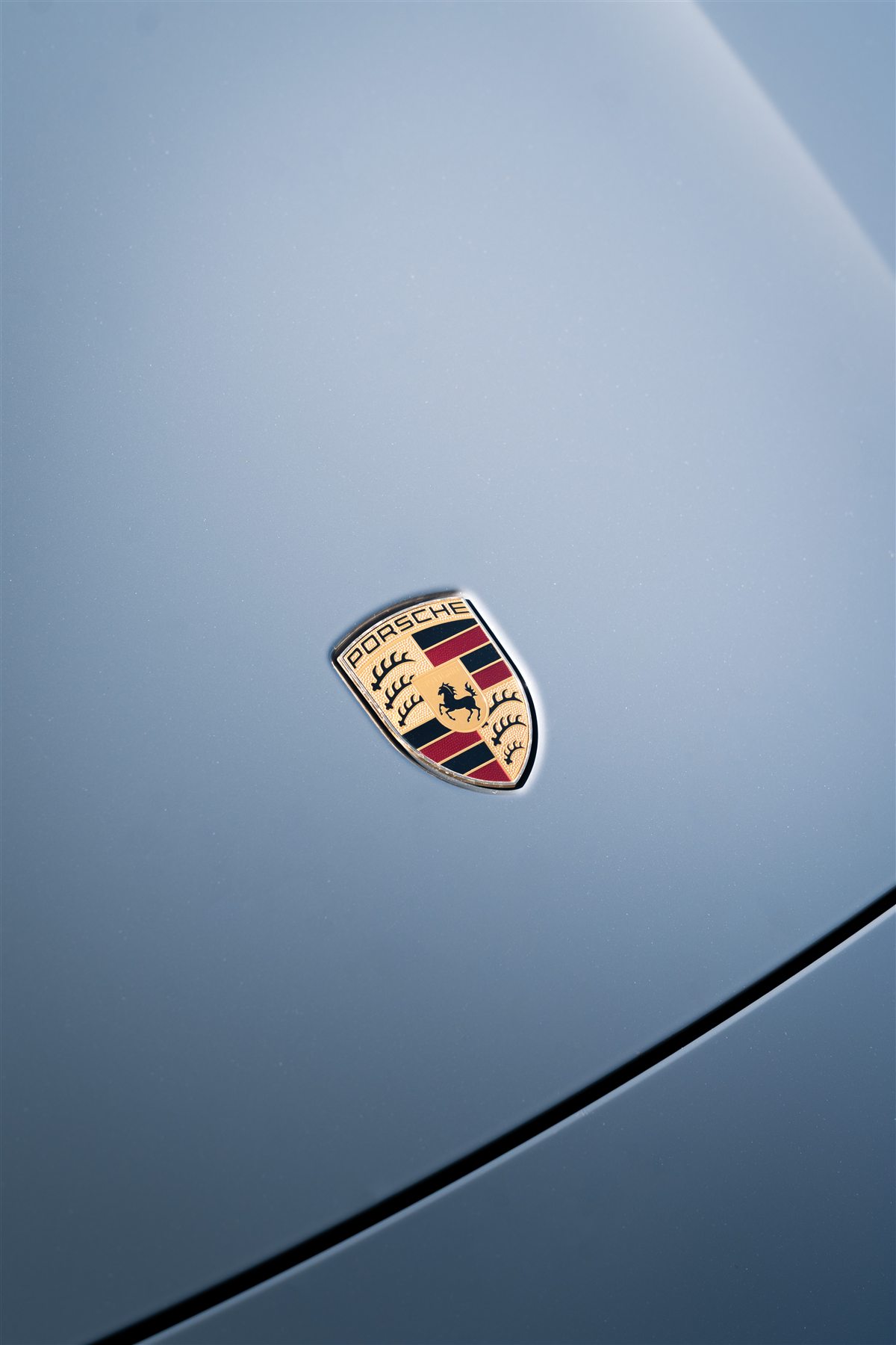 Het Porsche-logo op de grijze motorkap
